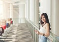 Young smiling business asian woman sitting near window and uses digital tablet Royalty Free Stock Photo