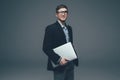 Young smiling business man holding laptop on grey Royalty Free Stock Photo