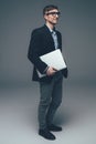 Young smiling business man holding laptop on grey Royalty Free Stock Photo