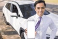 Young smiling business man showing mobile phone with white empty screen and standing before the car Royalty Free Stock Photo