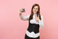 Young smiling business woman in glasses doing taking selfie shot on mobile phone pointing index finger on pink Royalty Free Stock Photo