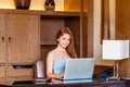 Young smiling business woman using laptop computer in modern apartment. Attractive businesswoman working from luxury Royalty Free Stock Photo