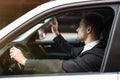 Young smiling businessman adjusting sunroof in his car before starting his trip , modern technologies concept