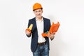 Young smiling businessman in dark suit, protective construction orange helmet holding opened case with instruments or