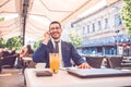 Young smiling businessman in glasses talking on the phone during coffee break in a cafe