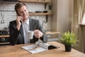 Young smiling businessman having pleasant conversation on his smartphone in the kitchen while drinking morning coffee before going Royalty Free Stock Photo