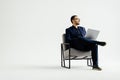 Young smiling businessman sitting in office chair and working on laptop on white background Royalty Free Stock Photo