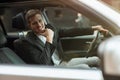 Young smiling businessman sitts in his car looks happy and satisfied, successful business strategy concept Royalty Free Stock Photo