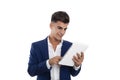 Young smiling businessman using a white tablet mobile. He is wearing a blue jacket suit and a white shirt. He is in a photo studio Royalty Free Stock Photo