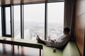 Young smiling businessman working on laptop computer wearing white bath robe sitting near window with cup of coffee Royalty Free Stock Photo