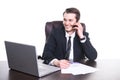 Young smiling businessman working at the office on laptop, talking on cell phone and smiling. Royalty Free Stock Photo