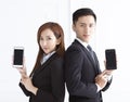 smiling businesswoman and businessman showing smart phone