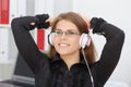 Young smiling businesswoman listening music in headphones, seen in top view. Rest from work in the office Royalty Free Stock Photo