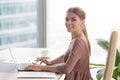 Young smiling businesswoman sitting at office desk looking at ca Royalty Free Stock Photo