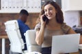 Young Smiling Businesswoman Working At Desk In Office Talking On Mobile Phone Royalty Free Stock Photo