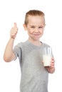 Young smiling caucasian boy with milky moustache holds glass of milk and shows thumbs up