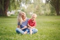 Young smiling Caucasian mother and laughing boy toddler son sitting on grass in park. Family mom and child hugging having fun Royalty Free Stock Photo