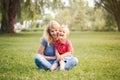 Young smiling Caucasian mother and laughing boy toddler son sitting on grass in park. Family mom and child hugging having fun Royalty Free Stock Photo