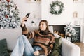 Young smiling caucasian woman making selfie using mobile phone near Christmas tree at home Royalty Free Stock Photo