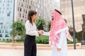 Young smiling caucasian woman and Saudi businessman shaking hands, greeting each other outdoors Royalty Free Stock Photo