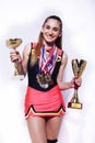 Young smiling cheerleader girl with golden cups and price medals isolated on white background, lifestyle sport people Royalty Free Stock Photo