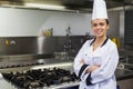 Young smiling chef standing arms crossed in front of hotplate