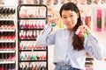 Young smiling Chinese woman holding lot of nail polish bottles in cosmetics store Royalty Free Stock Photo