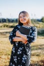Young smiling christian girl holding a bible under her arm in the field. Sola scriptura. Copy space Royalty Free Stock Photo