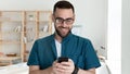 Young smiling company worker looking at mobile phone screen.