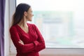 Young smiling confident woman stands near the window, female crossed her arms, woman in a knitted sweater Royalty Free Stock Photo