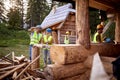 Young smiling constructer couple chatting on construction site. Other workers working in the background. Teamwork. Wooden Skeleton