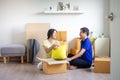 Young smiling couple bonding sitting on floor in new home with boxes on moving day. Happy homeowners or renters just moved into