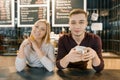 Young smiling couple of coffee shop workers, man and woman posing near the bar counter and coffee machine with cup of fresh coffee Royalty Free Stock Photo