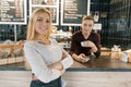 Young smiling couple of coffee shop workers, man and woman posing near the bar counter and coffee machine with cup of fresh coffee Royalty Free Stock Photo