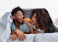 Young smiling couple eating breakfast in bed Royalty Free Stock Photo