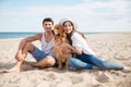 Young smiling couple in love sitting on beach with dog Royalty Free Stock Photo