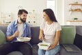 Young smiling couple office workers sitting on sofa and enjoying healthy boxed food