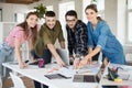 Young smiling creative people happily looking in camera working together with laptop. Group of cool guys working on new