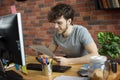 Young smiling designer or artist working at his workplace looking at color palette in loft style office Royalty Free Stock Photo