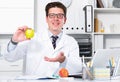 Doctor dentist in uniform demonstrating benefit of apples