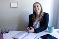 Young smiling entrepreneur woman holding a mobile phone while working at home Royalty Free Stock Photo