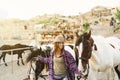 Young smiling farmer taking care of horses inside ranch