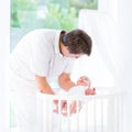 Young smiling father putting newborn baby in crib Royalty Free Stock Photo