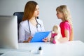 Young smiling female doctor and her little patient with teddy be Royalty Free Stock Photo