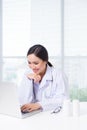 Young smiling female doctor sitting at office desk and working w Royalty Free Stock Photo