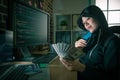 Young smiling female hacker looking at banknote