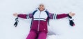 Young smiling female liying on the white snow wide opened her arms