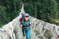 Young smiling female photographer crossing canyon over Suspension Bridge decorated with multicolored Tibetan Prayer flags hinged