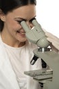 A young smiling female scientist looks through a microscope in a studio on a white