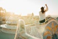 Young smiling female tourist spending vacation in Barcelona,Catalonia,Spain.Traveling to Europe,visiting Parc Guell.Best sunrise